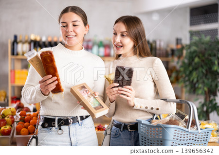 Two girls in store while shopping, choose sweets and chat sweetly Two girls in store while shopping, choose sweets and chat sweetly 139656342