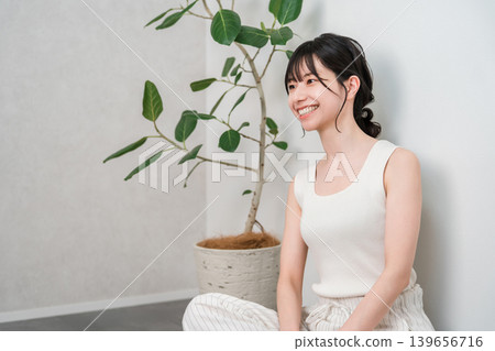 一位面帶甜美笑容的美麗亞洲女性側身坐在木地板上（美容，化妝品） 139656716
