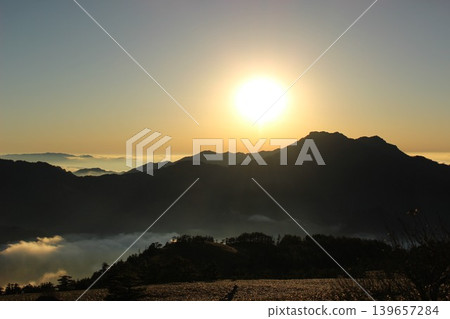 A sea of clouds illuminated by the setting sun and the silhouette of Mt. Ishizuchi, as seen from Mt. Kamegamori in the Ishizuchi mountain range of Ehime Prefecture. A sea of clouds illuminated by the setting sun and the silhouette of Mt. Ishizuchi, as seen from Mt. Kamegamori in the Ishizuchi mountain range of Ehime Prefecture. 139657284