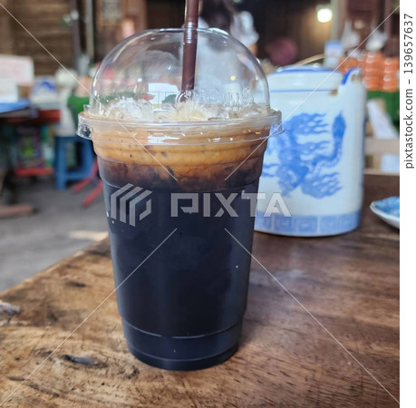 Iced Thai Black Coffee in a Plastic Cup on a Rustic Wooden Table Iced Thai Black Coffee in a Plastic Cup on a Rustic Wooden Table 139657637