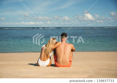 Couple sits on the sand and watches the ocean waves Couple sits on the sand and watches the ocean waves 139657733