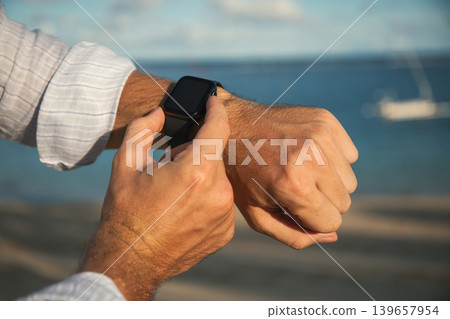 Person using a smartwatch by the water in Bali during summer 139657954