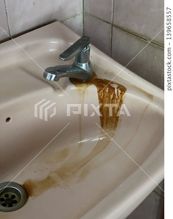 Old Pink Bathroom Sink With Rusty Stains And Leaking Faucet Old Pink Bathroom Sink With Rusty Stains And Leaking Faucet 139658557