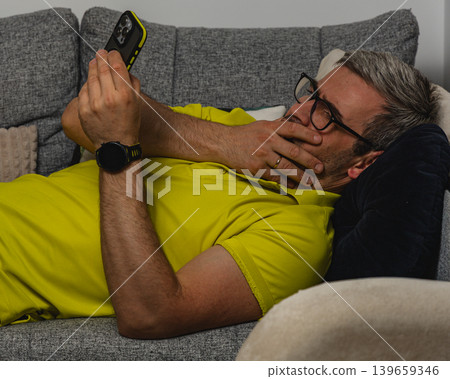 Tired man relaxing with smartphone after work 139659346
