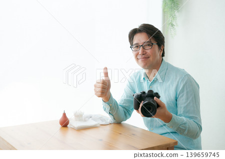 A man smiling with a camera in his hand. 139659745