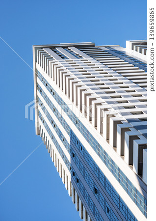 Modern high-rise residential buildings with glass facades against a clear blue sky. Modern high-rise residential buildings with glass facades against a clear blue sky. 139659865