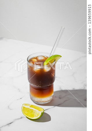 Cold Coffee Tonic Drink With Lime and Ice on light background with shadows Cold Coffee Tonic Drink With Lime and Ice on light background with shadows 139659915