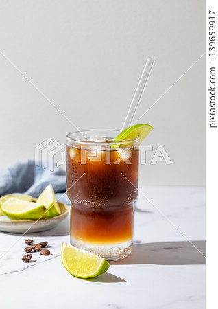 Cold Coffee Tonic Drink With Lime and Ice on light background with shadows Cold Coffee Tonic Drink With Lime and Ice on light background with shadows 139659917