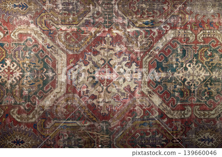 Worn vintage oriental rug featuring a faded Persian medallion pattern, rich muted colors Worn vintage oriental rug featuring a faded Persian medallion pattern, rich muted colors 139660046