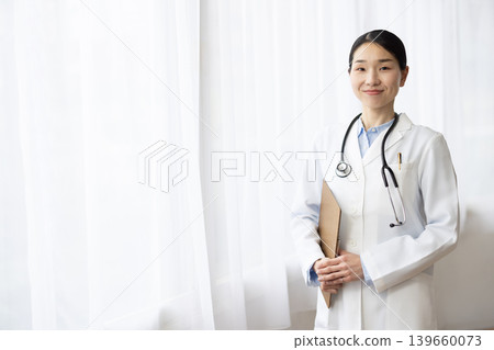 一位身穿白大褂的日本女醫生在明亮的窗邊微笑。 139660073