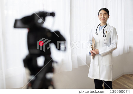 A Japanese female doctor smiles in front of a video camera. 139660074