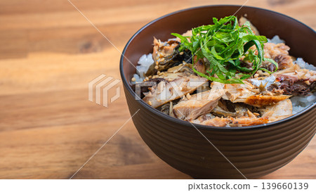 Grilled mackerel rice bowl with shredded mackerel and shiso leaves, served on a wooden table. Grilled mackerel rice bowl with shredded mackerel and shiso leaves, served on a wooden table. 139660139