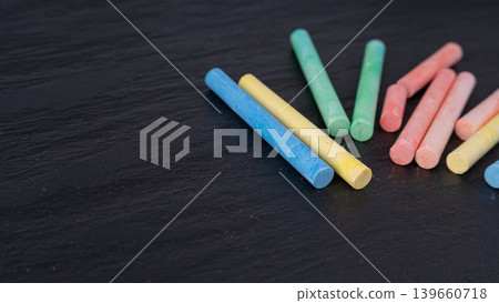Colorful chalks pile on black background, different colors crayons on dark stone plate Colorful chalks pile on black background, different colors crayons on dark stone plate 139660718