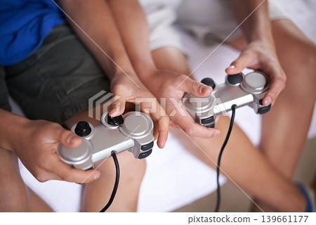 Children, hands and video game controller in a house for gaming, subscription or entertainment closeup from above. Gamepad, zoom and gamer boy kids at home with esports, competition or challenge Children, hands and video game controller in a house for gaming, subscription or entertainment closeup from above. Gamepad, zoom and gamer boy kids at home with esports, competition or challenge 139661177