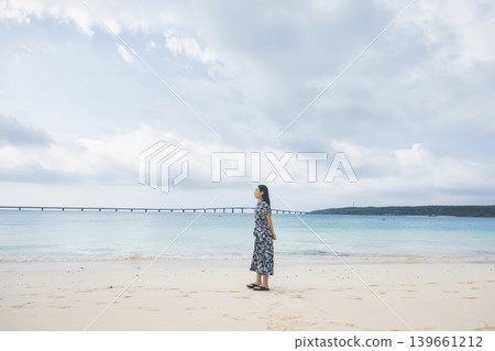一位女士從與那霸前濱海灘眺望久里馬大橋。 一位女士從與那霸前濱海灘眺望久里馬大橋。 139661212