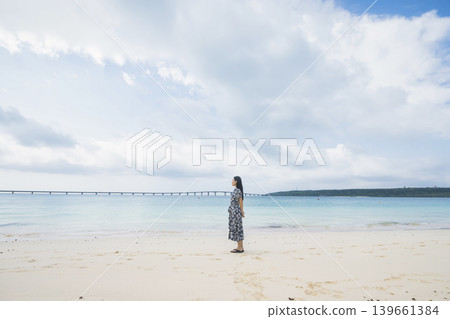 A woman looking at Kurima Bridge from Yonaha Maehama Beach. A woman looking at Kurima Bridge from Yonaha Maehama Beach. 139661384