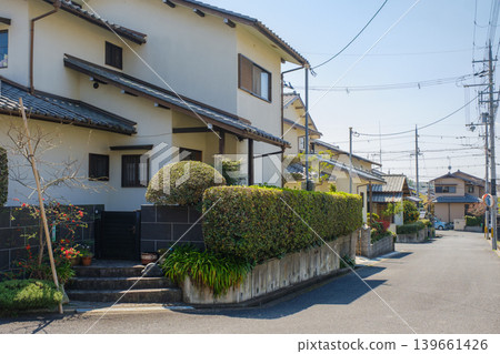 日本寧靜的住宅街景:修剪整齊的樹籬和湛藍的天空營造出寧靜的日常生活。 日本寧靜的住宅街景:修剪整齊的樹籬和湛藍的天空營造出寧靜的日常生活。 139661426