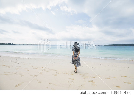 一位戴著草帽的女子從與那霸前濱海灘眺望久里馬大橋。 一位戴著草帽的女子從與那霸前濱海灘眺望久里馬大橋。 139661454