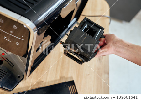Person removing brewing unit from coffee machine for maintenance Person removing brewing unit from coffee machine for maintenance 139661641