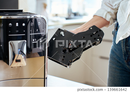 Woman removing internal unit from coffee machine Woman removing internal unit from coffee machine 139661642
