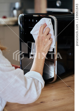 Woman cleaning coffee machine with white cloth 139661643