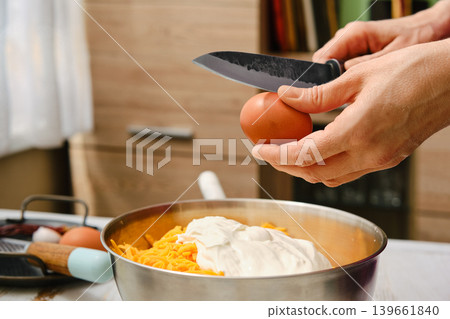 Hands prepare ingredients for meal in kitchen while cracking egg over bowl Hands prepare ingredients for meal in kitchen while cracking egg over bowl 139661840