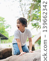 Joyful Young Girl Playing Outdoors on a Tree Trunk in a Lush Green Park with a Bright Sunny Day and Natural Background Ideal for Children's Activities 139662342