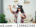 Young Child Engaged in Virtual Reality Experience at Home with Excitement and Curiosity While Wearing VR Headset and Reaching Out for Interaction 139662348