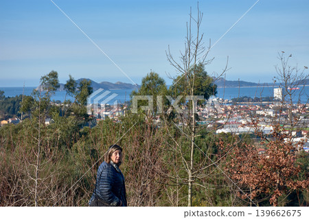 Woman standing on a mountain road in San Andres de Comesana, Vigo, with Vigo Bay behind Woman standing on a mountain road in San Andres de Comesana, Vigo, with Vigo Bay behind 139662675