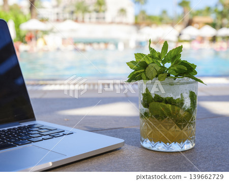 mojito and laptop in a hotel pool mojito and laptop in a hotel pool 139662729