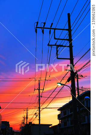 A scene of a city at dusk with the sunset sky and telephone poles. A scene of a city at dusk with the sunset sky and telephone poles. 139662865