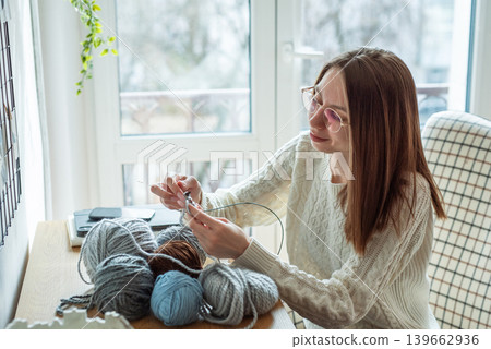 Woman knitting wool yarn at home for hobby Woman knitting wool yarn at home for hobby 139662936