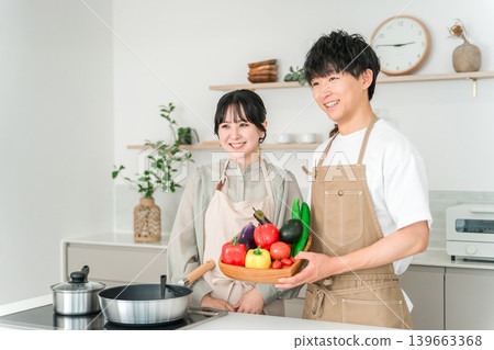 一對年輕的亞裔男女在廚房裡拿著蔬菜,他們是夫妻。 一對年輕的亞裔男女在廚房裡拿著蔬菜,他們是夫妻。 139663368