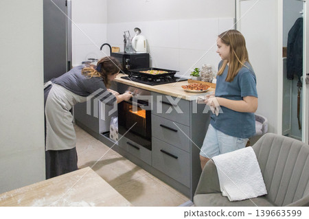 Cooking. Mother and daughter cooking italian pizza together in cozy home kitchen. 139663599
