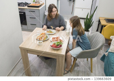 Young child and mother eating pizza at home Young child and mother eating pizza at home 139663609