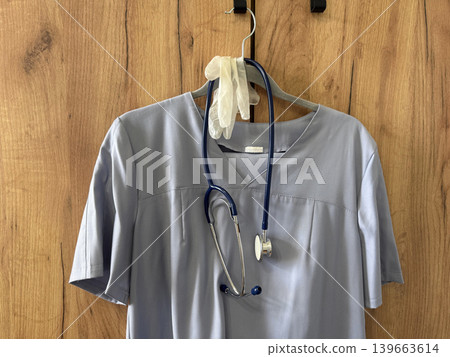 White coat hangs on a hanger next to medical supplies and a stet White coat hangs on a hanger next to medical supplies and a stet 139663614