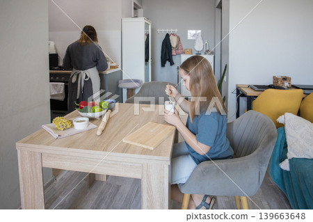 Cute child at home. Female family, mother and young daughter in kitchen Cute child at home. Female family, mother and young daughter in kitchen 139663648