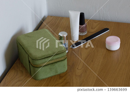 Green cosmetic case with nail polish, cream, and tools on wooden table in a well-lit indoor setting Green cosmetic case with nail polish, cream, and tools on wooden table in a well-lit indoor setting 139663699