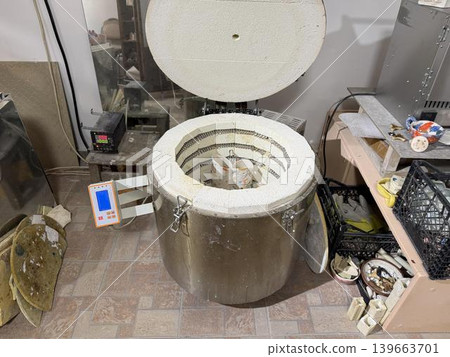 A kiln sits open in a pottery studio. Various tools and materials are spread out on tables. A kiln sits open in a pottery studio. Various tools and materials are spread out on tables. 139663701