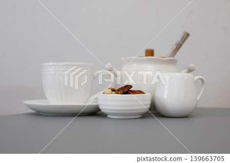 Teacups and snack bowl on a gray table with a teapot and creamer at a quiet afternoon tea setting Teacups and snack bowl on a gray table with a teapot and creamer at a quiet afternoon tea setting 139663705