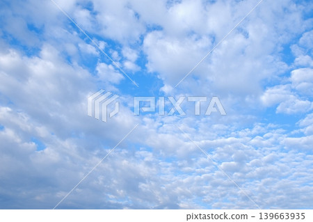 Background image of a vast expanse of cirrocumulus clouds and white wispy clouds against a blue sky. Background image of a vast expanse of cirrocumulus clouds and white wispy clouds against a blue sky. 139663935