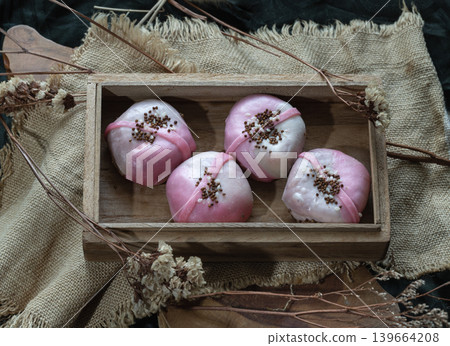 our Strawberry Cream Cheese Mochi reimagines a classic treat with artisanal flair. Presented in a traditional wooden tray and accented with crisp toasted toppings, these soft, pillowy bites offer a 139664208