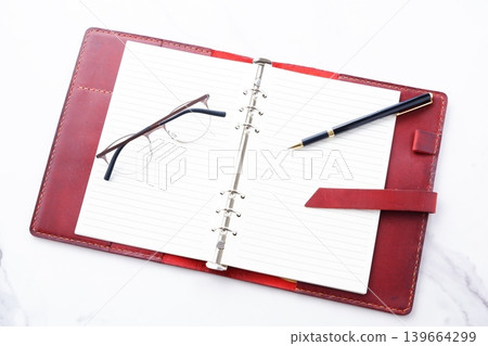 Image of a wine-red leather organizer doing desk work Image of a wine-red leather organizer doing desk work 139664299
