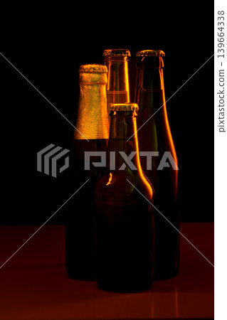 silhouettes of four beer bottles on a black background and lit with red light 139664338