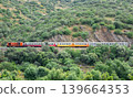 Passenger train traveling through green hills of Douro Valley in Portugal 139664353