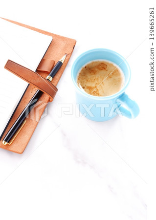 Image of a man working at his desk with a brown leather organizer while drinking a cafe latte, a coffee with milk Image of a man working at his desk with a brown leather organizer while drinking a cafe latte, a coffee with milk 139665261