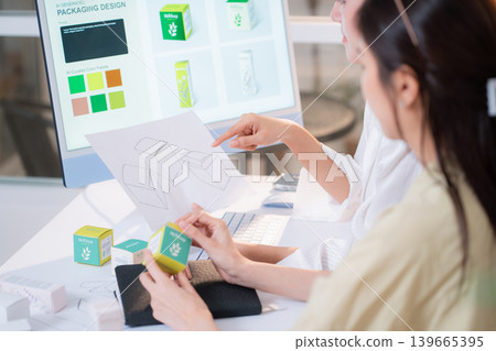 Two asian woman graphic designers analyzing product package prototype. Two asian woman graphic designers analyzing product package prototype. 139665395