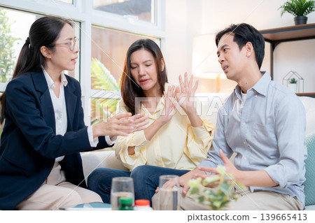 Asian couple arguing with therapist during home consultation. Asian couple arguing with therapist during home consultation. 139665413