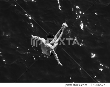 a professional male diver is jumping off a cliff into the sea a professional male diver is jumping off a cliff into the sea 139665740