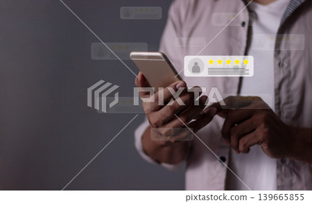 Young Man hand holding Smart Phone with five star to review and give 5 stars Young Man hand holding Smart Phone with five star to review and give 5 stars 139665855